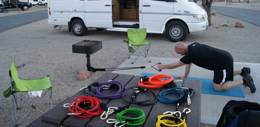 Man performing demonstration of resistant bands in use with multiple options of different resistant bands on display