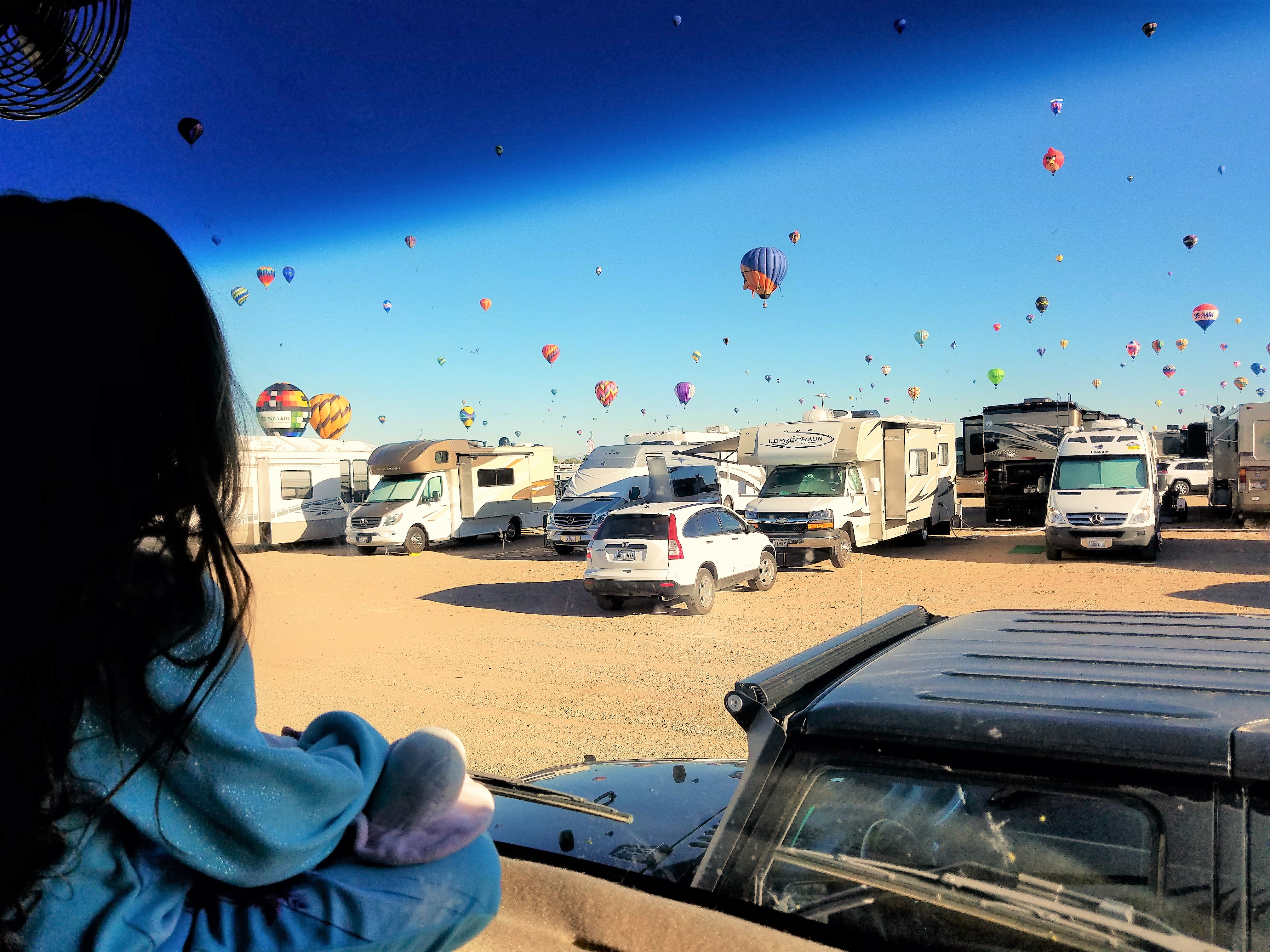 Hot air balloons fill the sky above RVs.