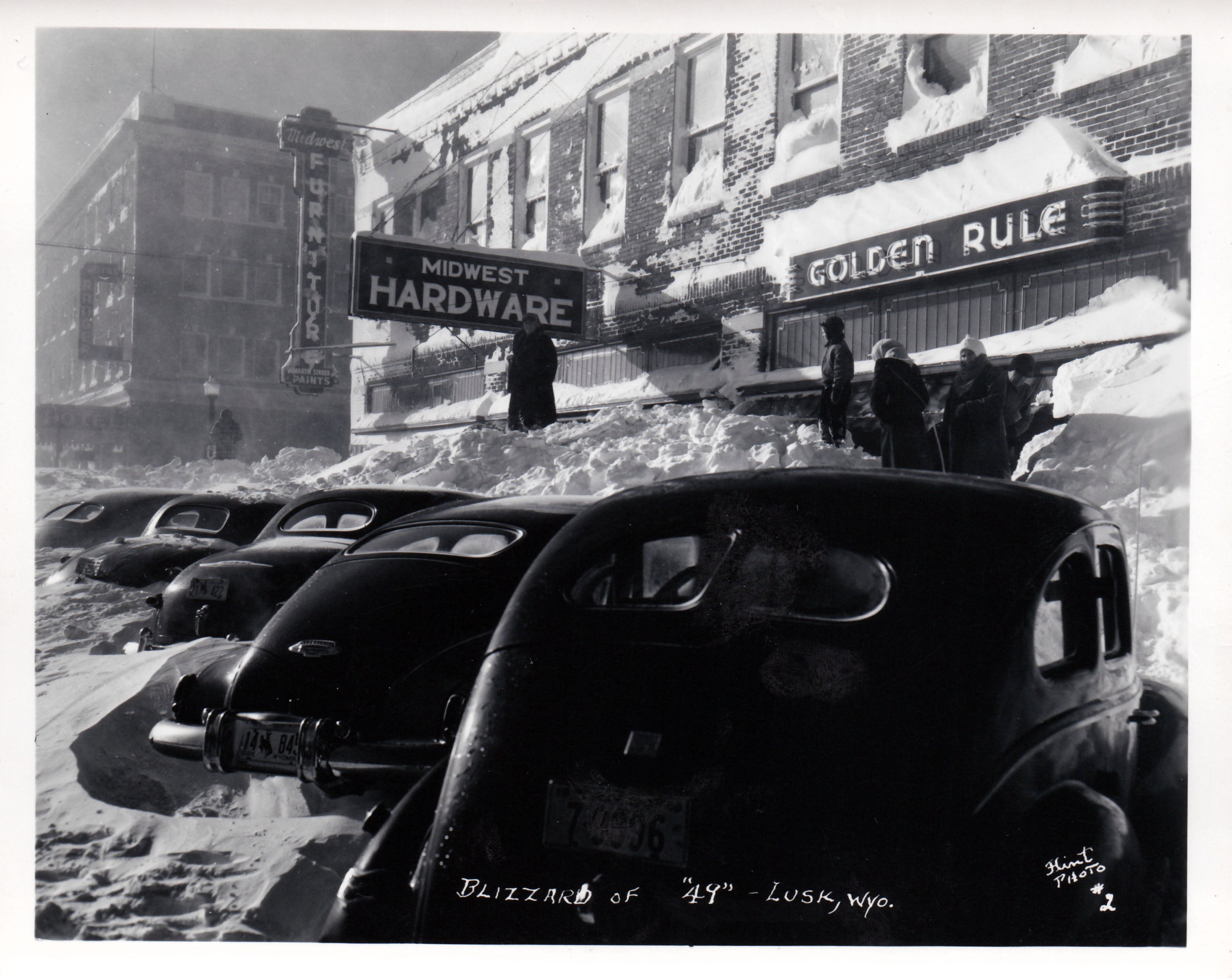 Old photo of cars and downtown area covered in snow.