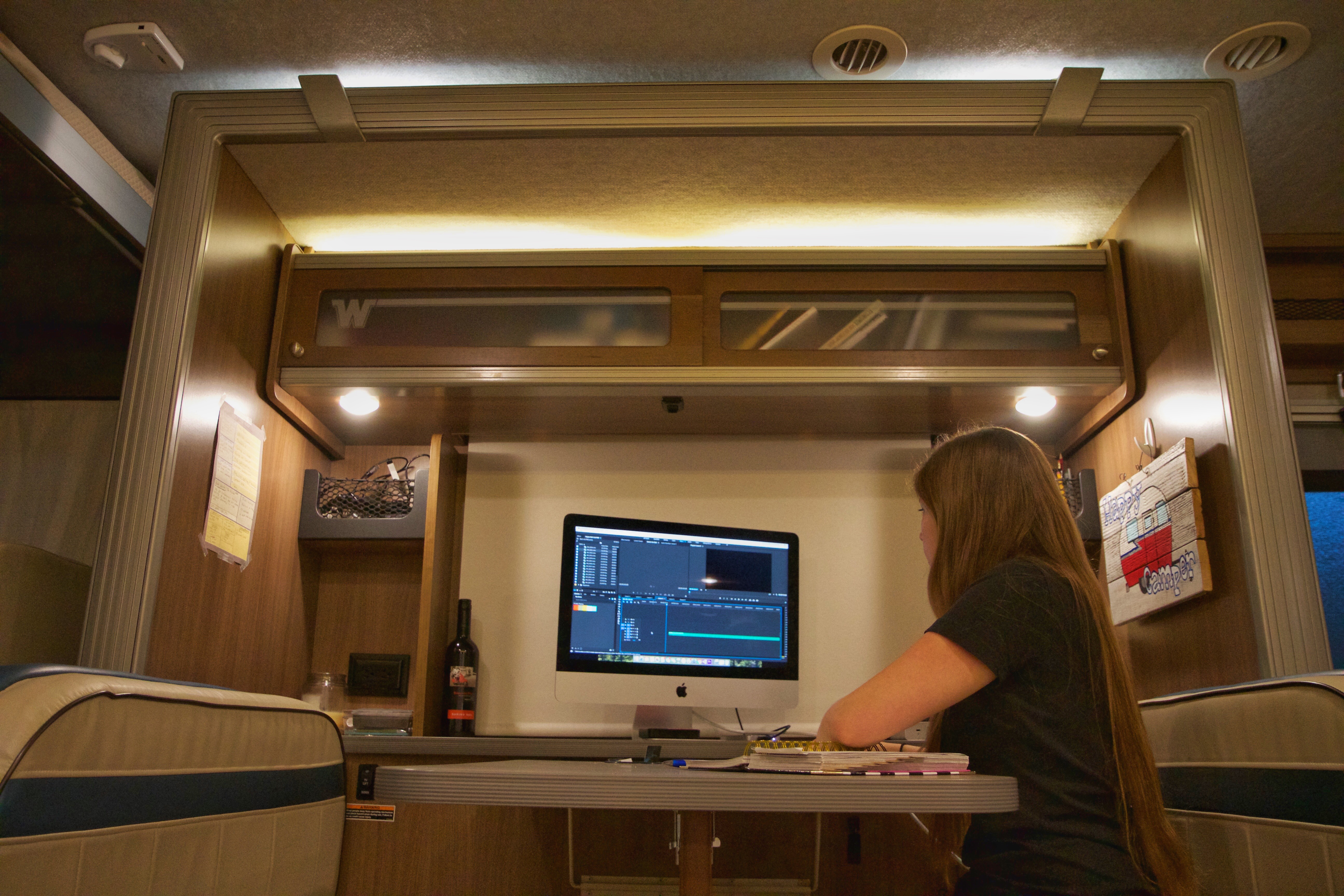 Woman working on a computer at motorhome dinette.