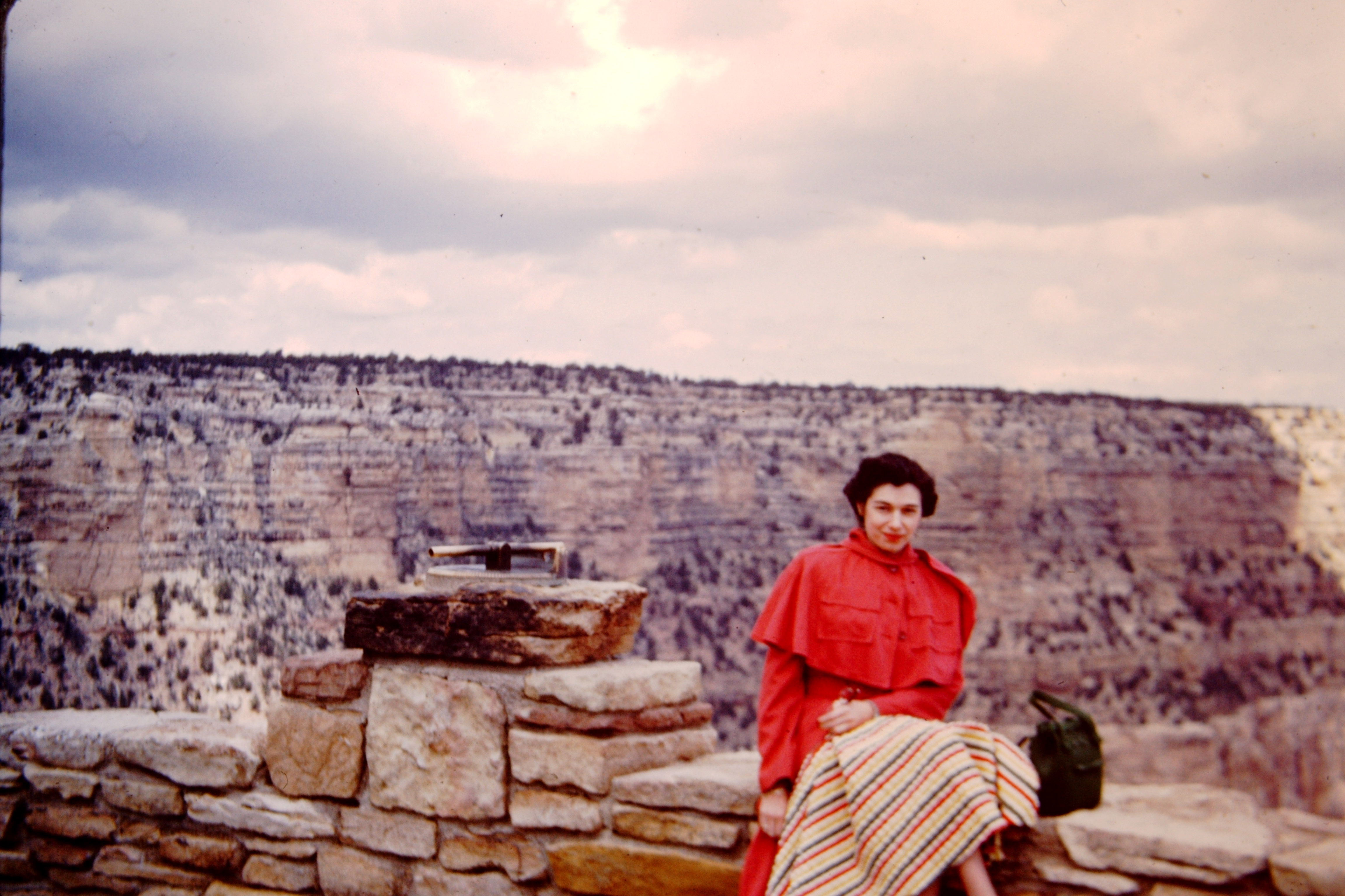 Old photo of a woman at the edge of the Grand Canyon.