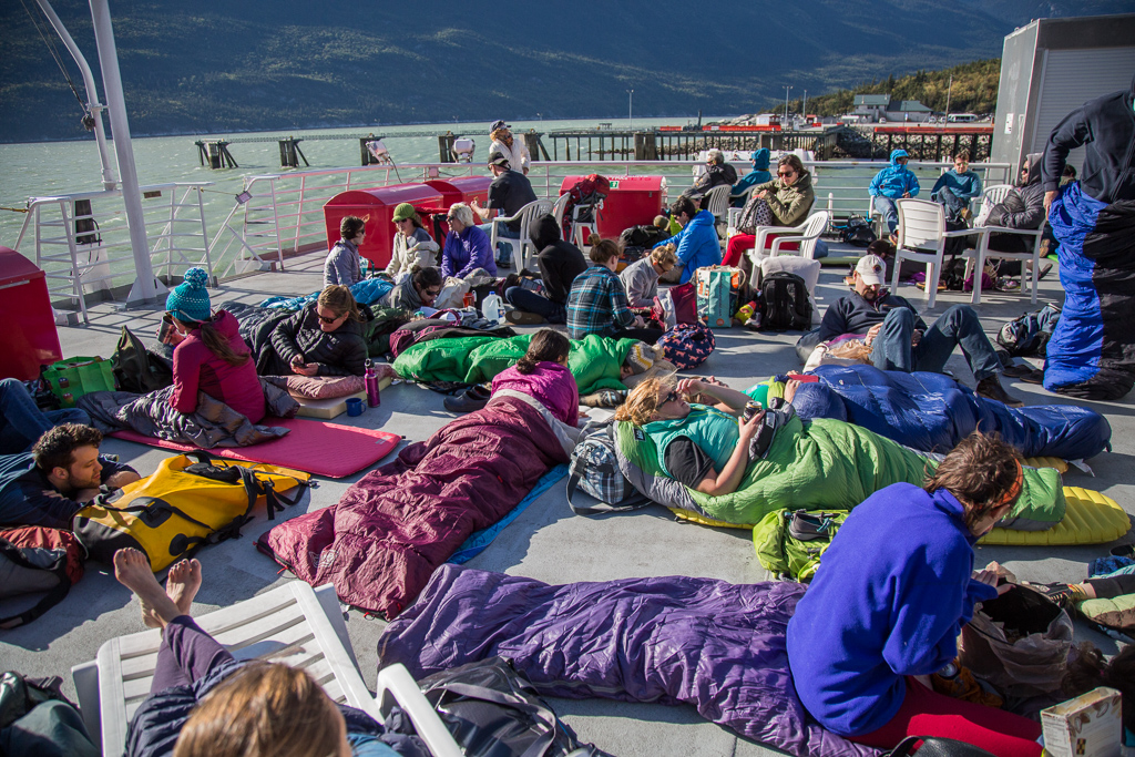 Large group gathered in chairs, sleeping bags across the upper deck of the boat.