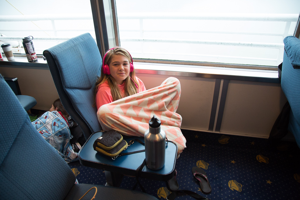 Abby in a chair with a blanket wrapped around her and headphones on.