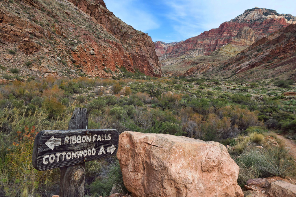 Sign pointing to Cottonwood one way and Ribbon Falls the other with Rocky canyons ahead.