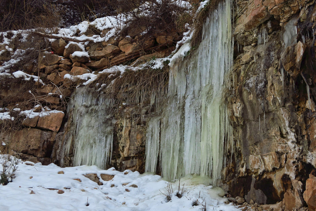 Large ice formations down the side of a rocky hill.
