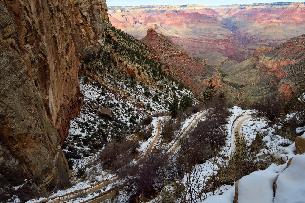 Snow covered path of switchbacks that leads into the dry depths of the canyon beyond.