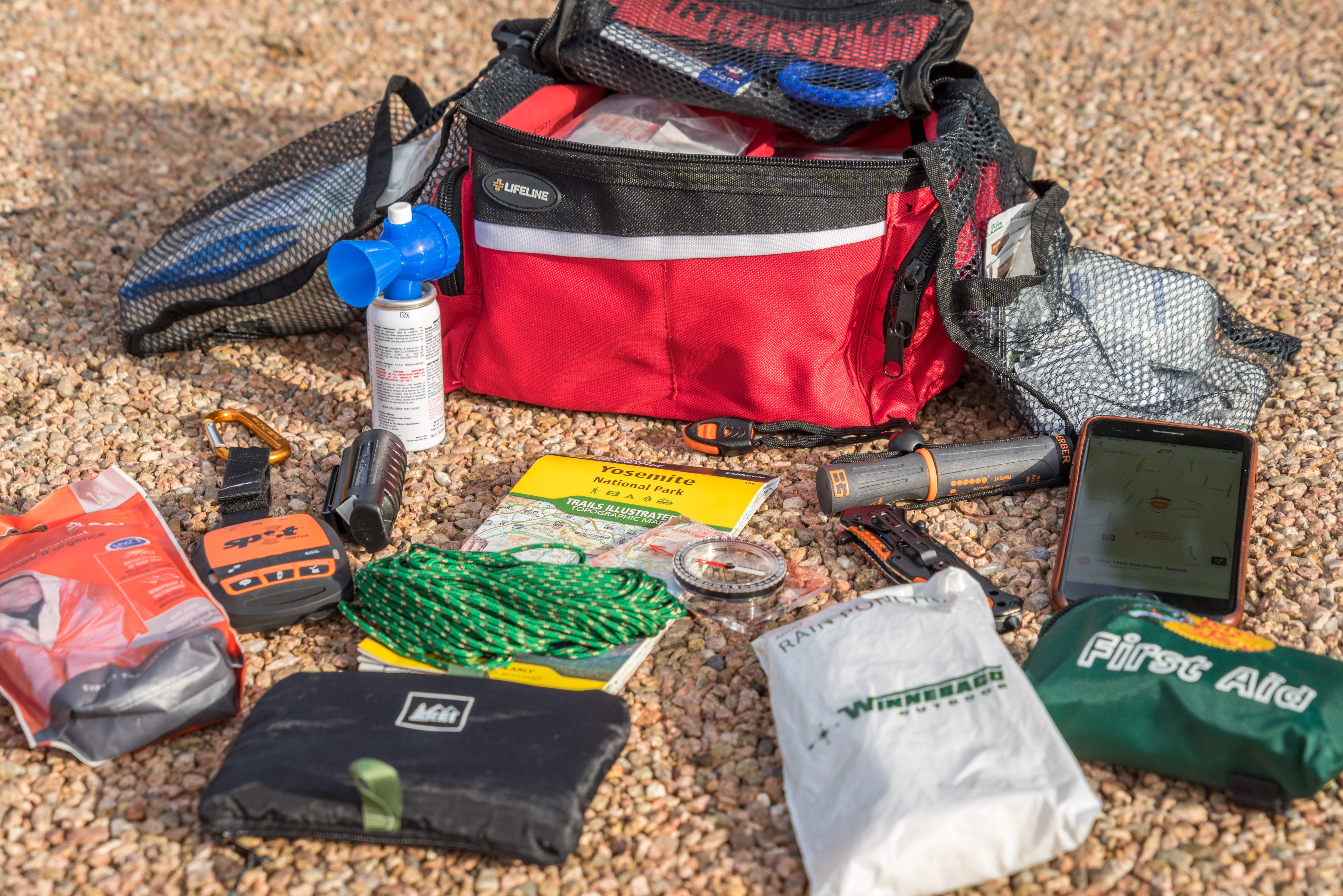 Emergency first aid kit with contents spread out on the ground.