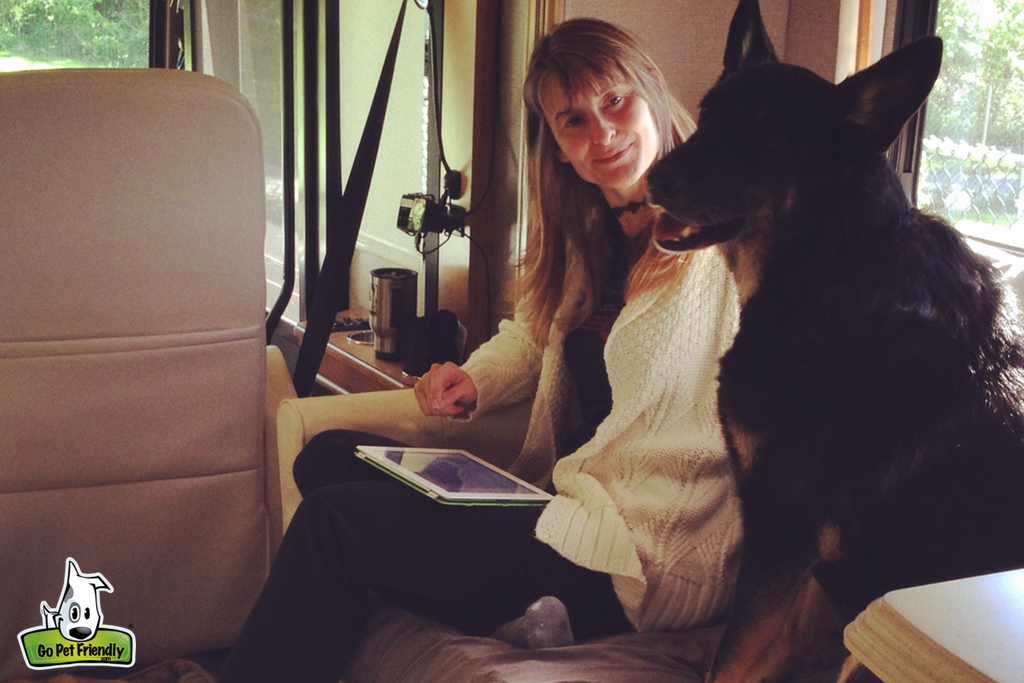 Woman sitting next to dog on a couch.