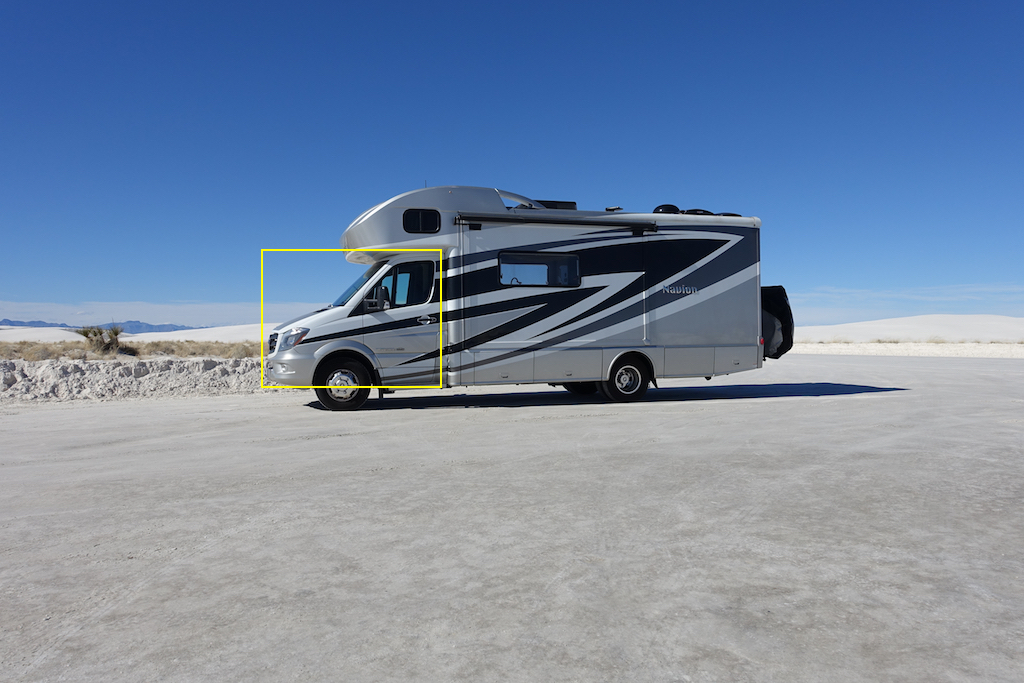 Driver's side exterior view of Winnebago Navion parked in the desert