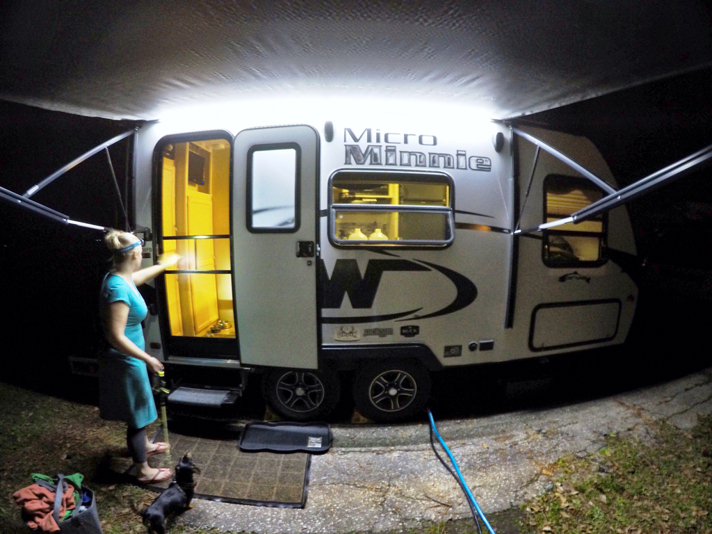 Woman and dog standing outside Winnebago Micro Minnie at night.
