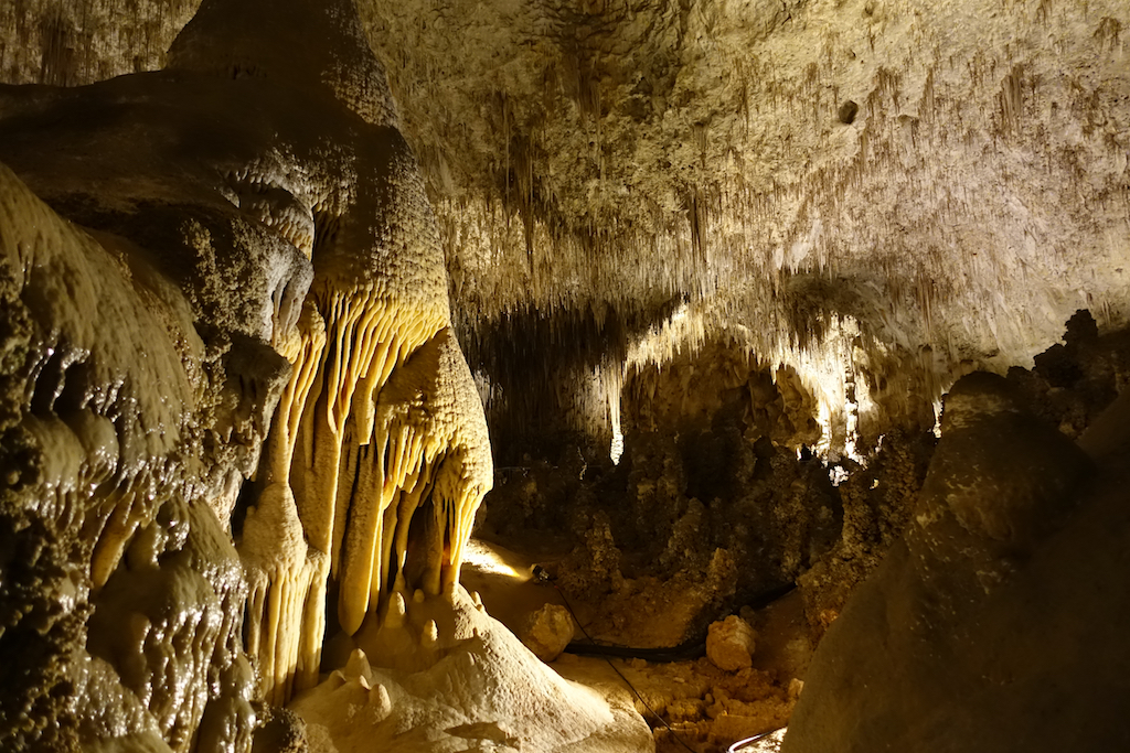 Incredible formations of stalagmites and stalactites within the cavern lit up by lights.