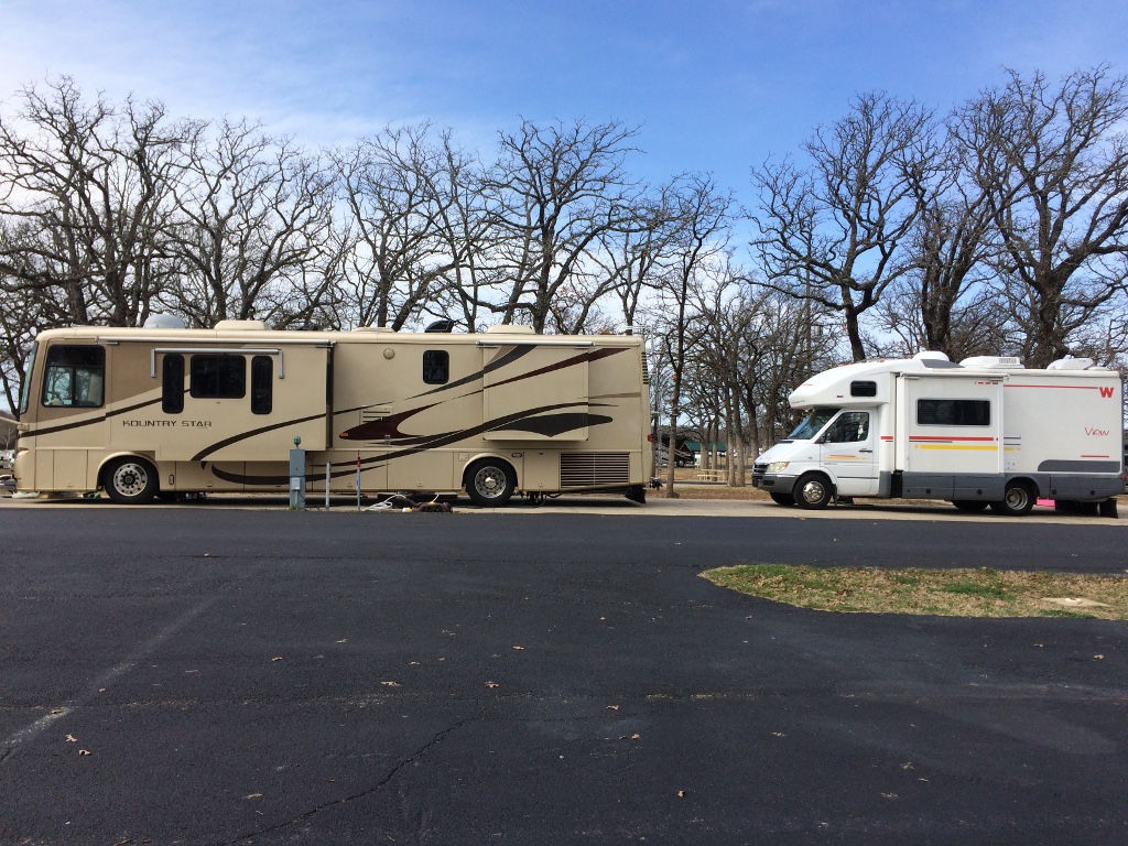 Large class A motorhome with Winnebago View parked behind it.