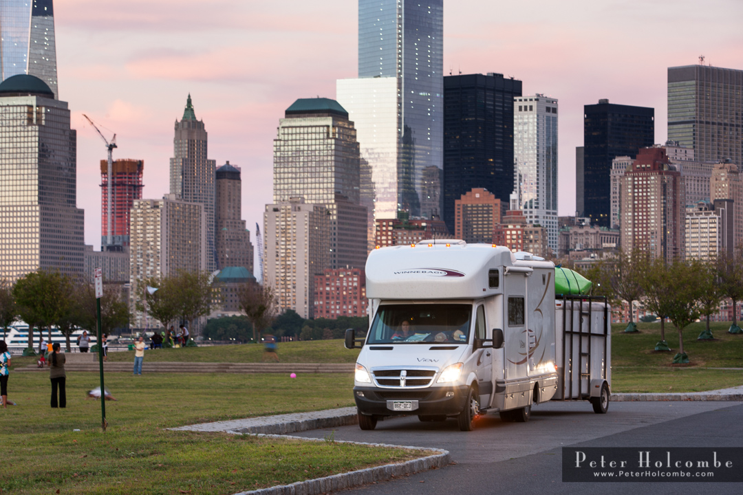 Winnebago View with trailer attached parked with a city skyline in the background.