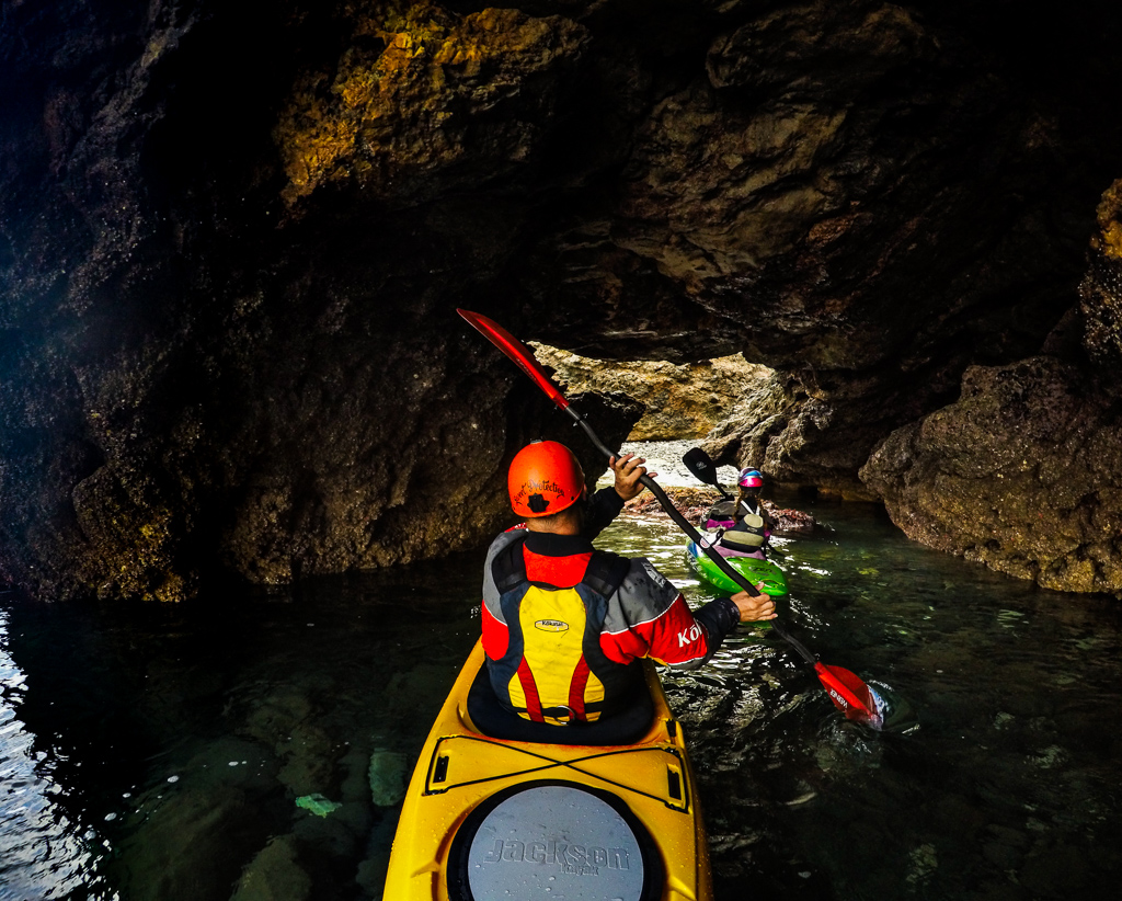 Abby and Peter in kayaks making their way through a tunnel in the sea caves.