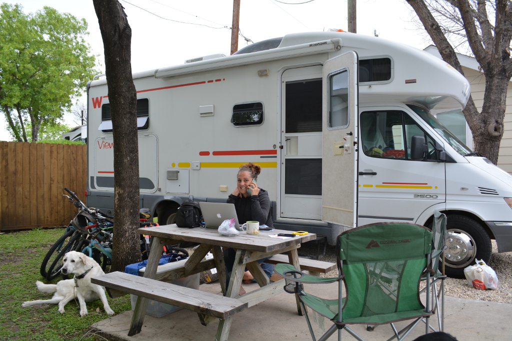 Bryanna working on her laptop at a picnic table outside a Winnebago View.