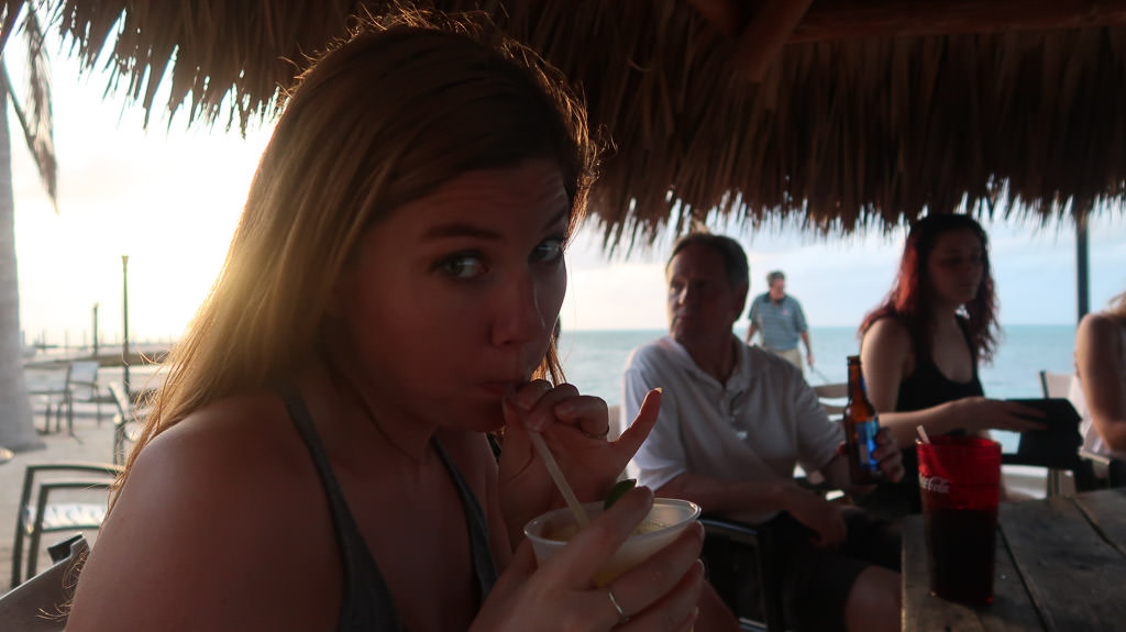 Alyssa sipping on a drink at a tiki bar.