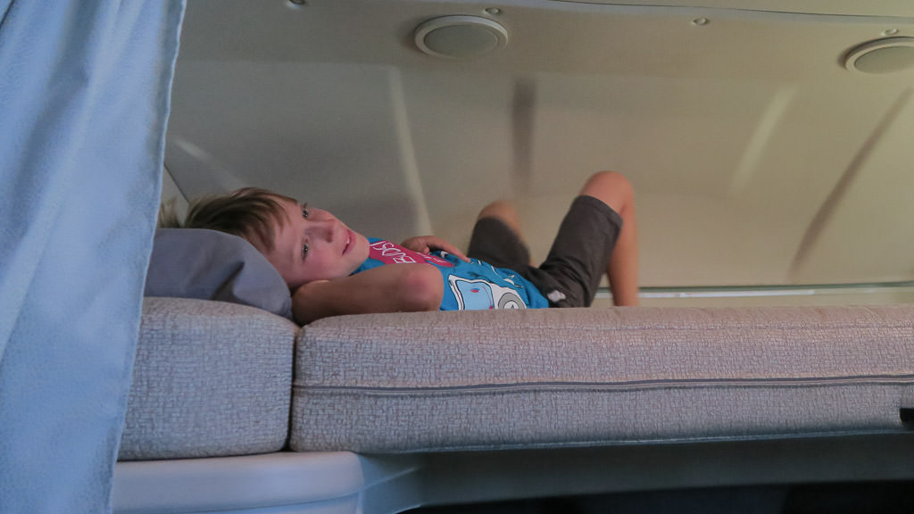 Child laying down in above cab RV bunk.