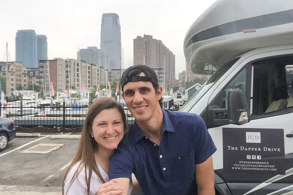 Jordan and Brittany standing next to their Winnebago View with NYC behind them.