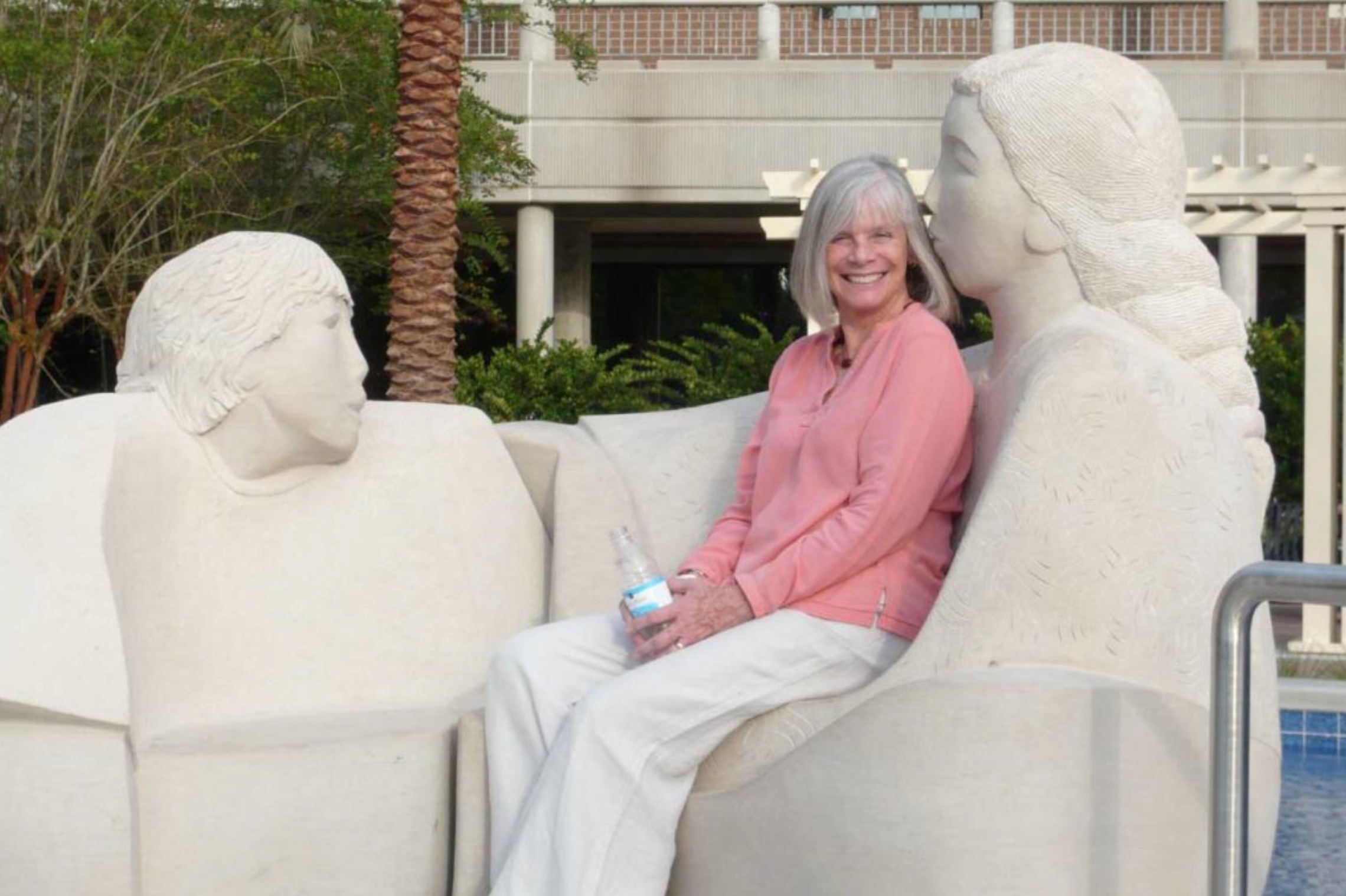 Sculptor Madeline Wiener sitting on one of her sculptors that represents two people.