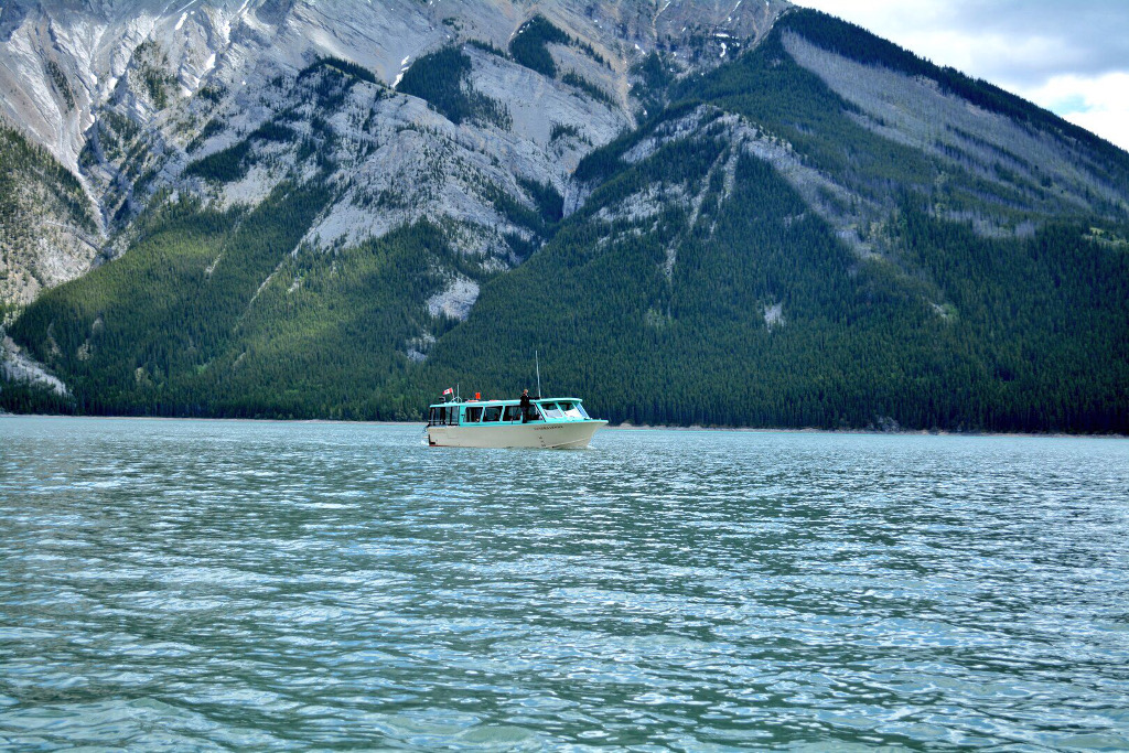 Boat out on the water at the base of a mountain.