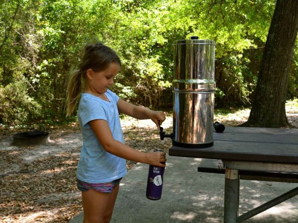 Young girl filling water bottle using the portable Berkey water filter 