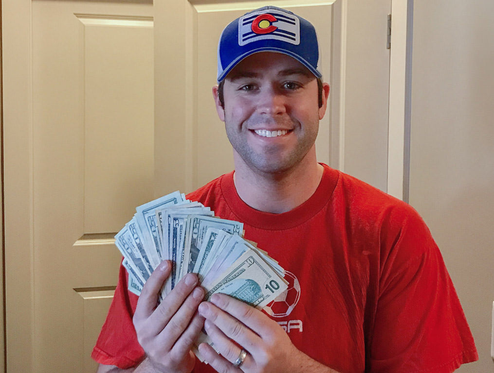 Dan smiling while holding a large amount of cash in his hands.