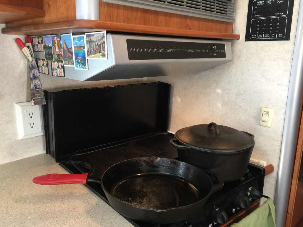 RV kitchen area with pans on the stove top.