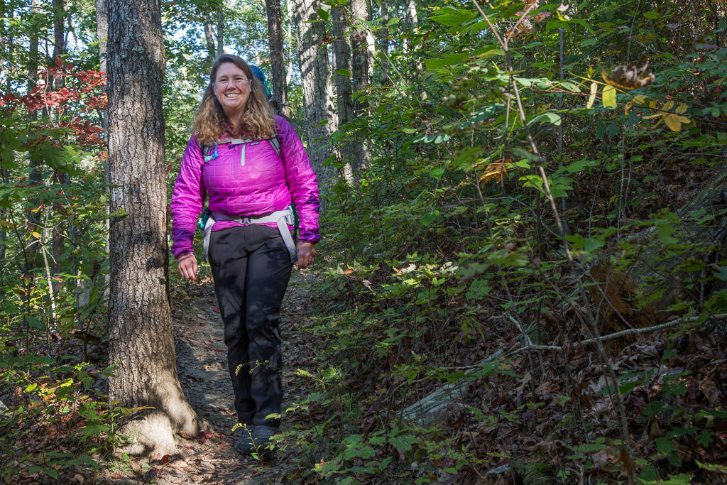 Kathy walking along narrow tree-lined trail.