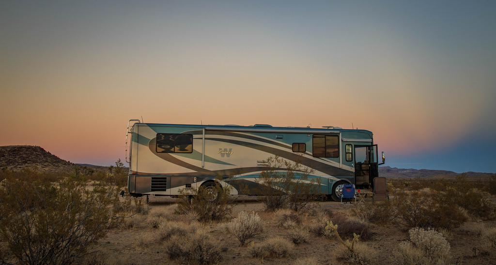 Winnebago Journey parked in desert with colorful sky above