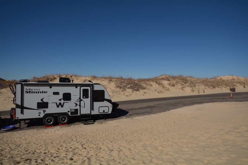 Winnebago Micro Minnie on a paved road next to the sand.