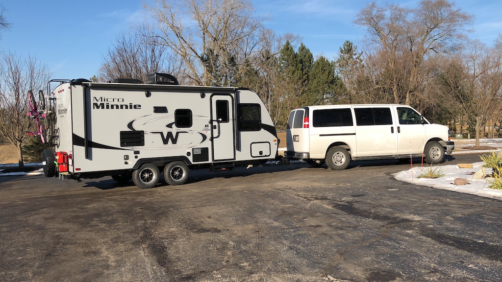 Winnebago Micro Minnie hooked up to a 12 passenger van in a parking lot.