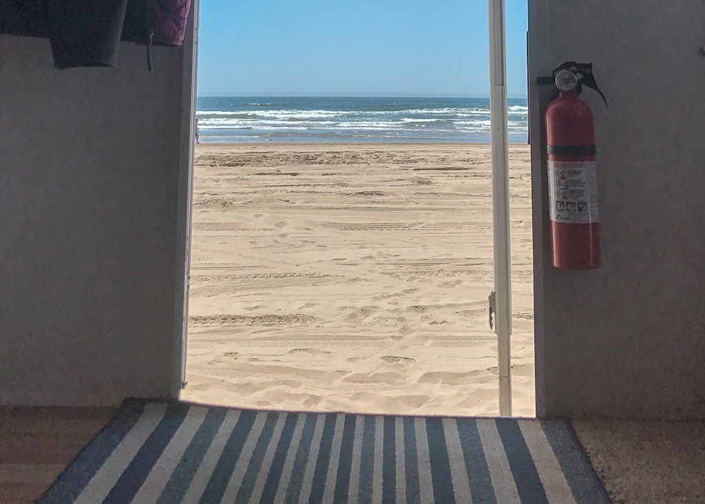 View of the beach and ocean from the door of a RV