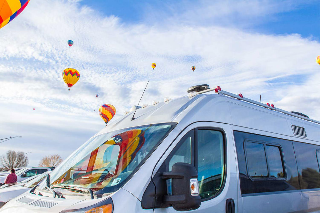 Travato parked under sky of hot air balloons at Balloon Festival in New Mexico