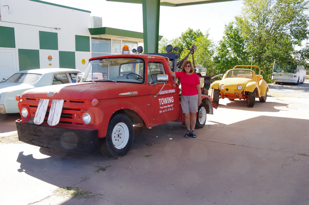 Woman at Peach Springs Caverns RV Park posing by old car