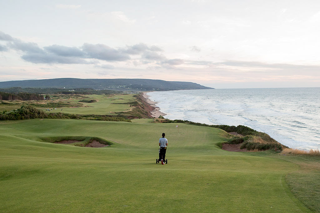 Person strolling the cliff-side fairway with water to the right