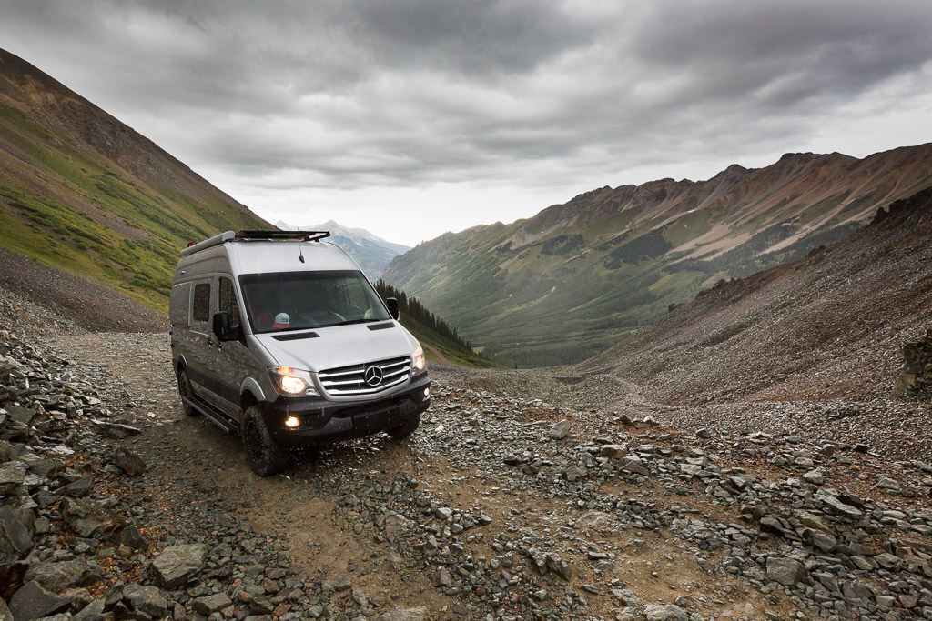 Winnebago Revel driving over rough ground in the mountains.