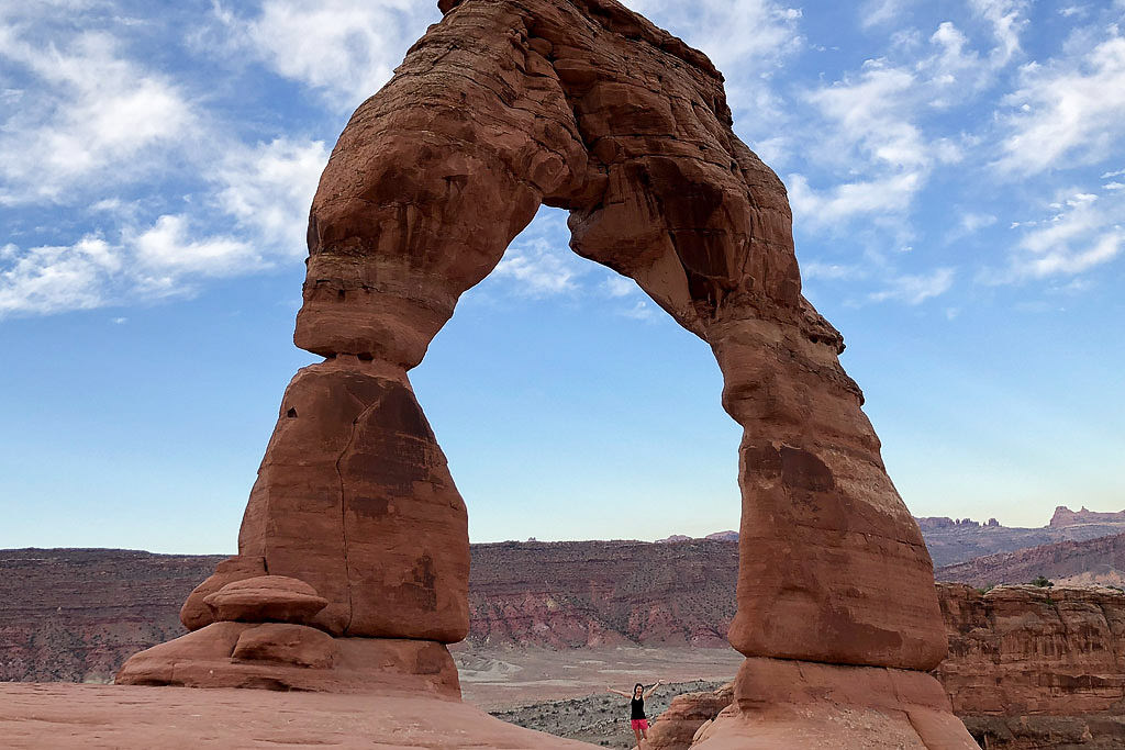 Brittany posing under the delicate arch in Arches National Park