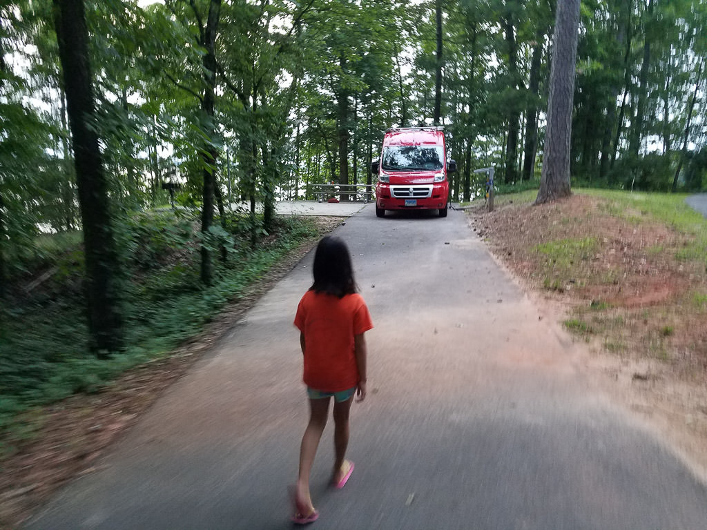 Red van parked in site with younger girl walking towards it