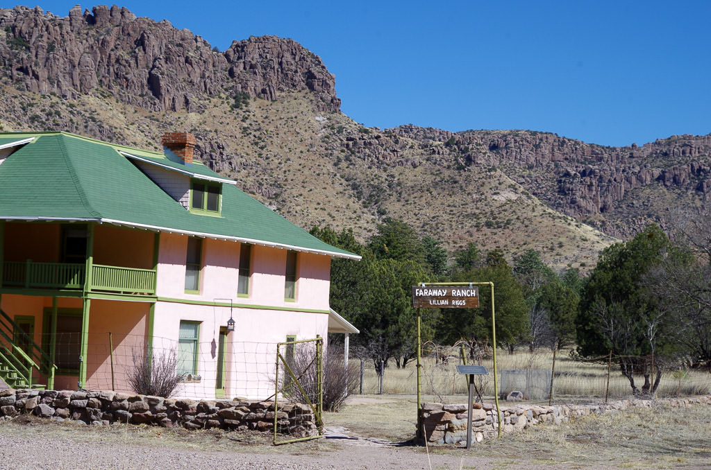 House with sign out front that says. "Faraway Ranch" and rocky hillsides and rock formations in the background.