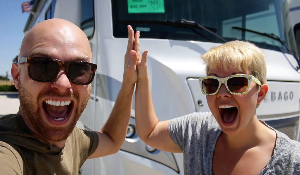 Nic and Jess  doing a high-five while standing outside their Winnebago Intent.
