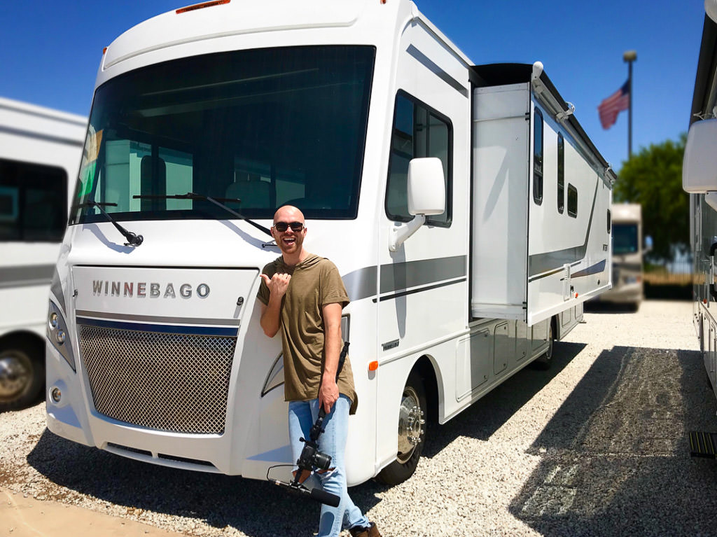 Nic standing outside the Winnebago Intent among other RVs at a dealership.