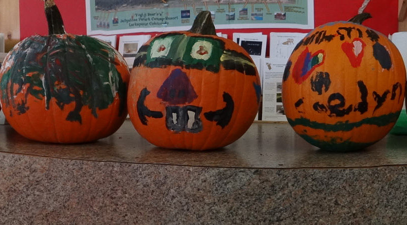 Three painted pumpkins sitting on a counter.