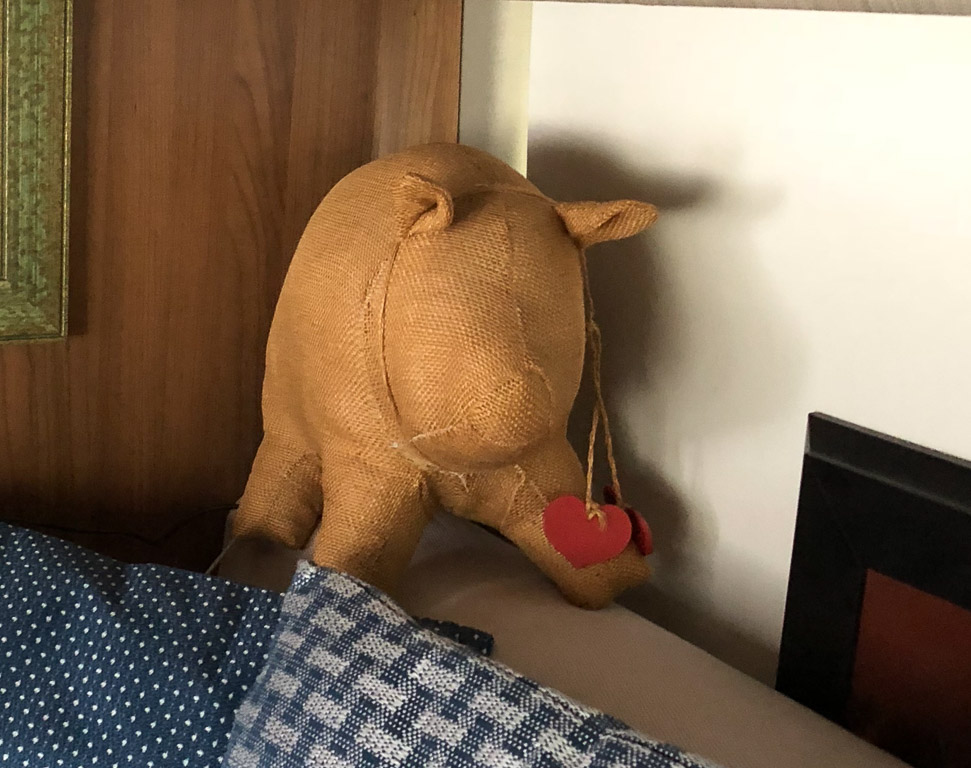Stuffed burlap pig sitting on bed