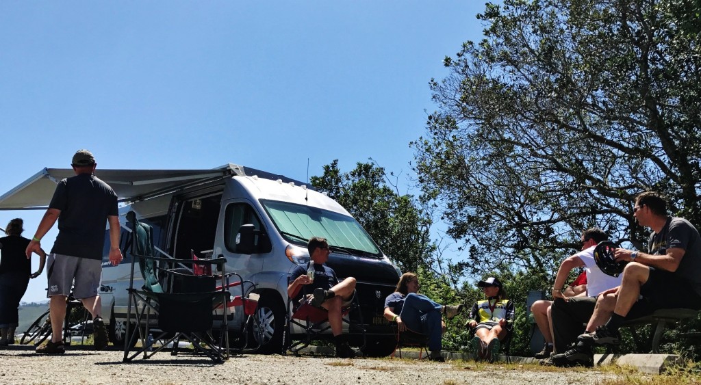 Group of Winnebago camping attendees sitting outside of Travato