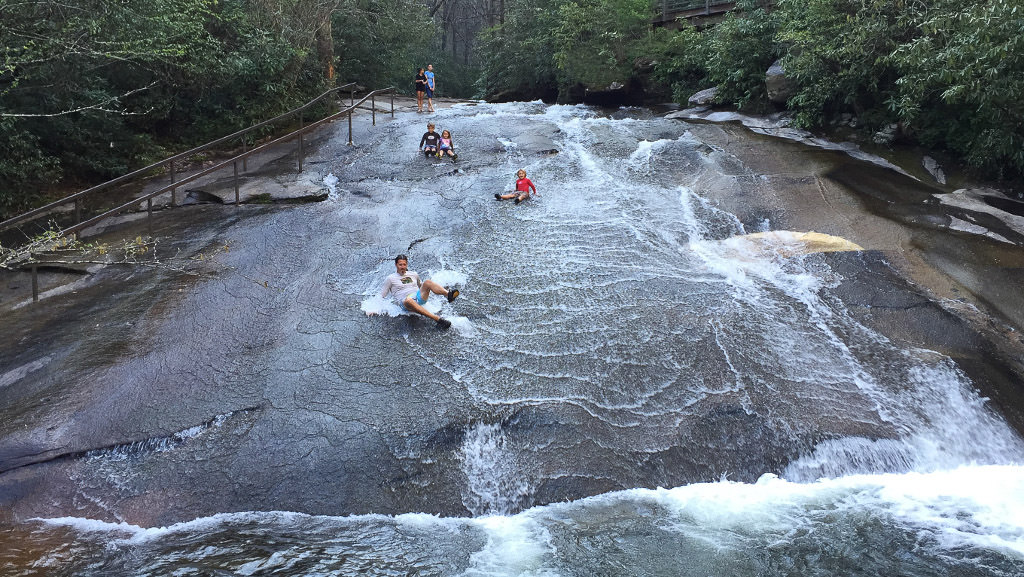 Family sliding down Sliding Rock, a natural waterfall slide.