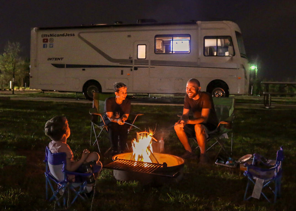 Farish family roasting hot dogs over campfire