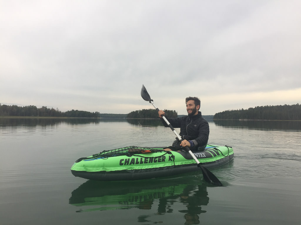 Young man paddling inflatable kayak on a lake