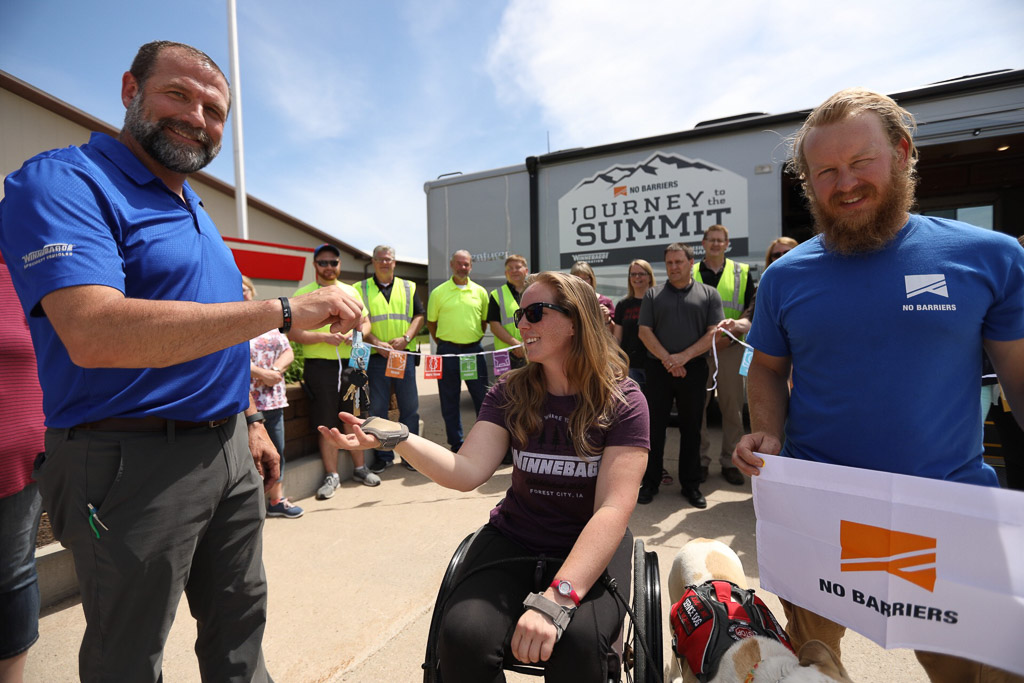 Nerissa Cannon being handed the keys to the accessibility equipped Winnebago Adventurer 30T which is parked in the background