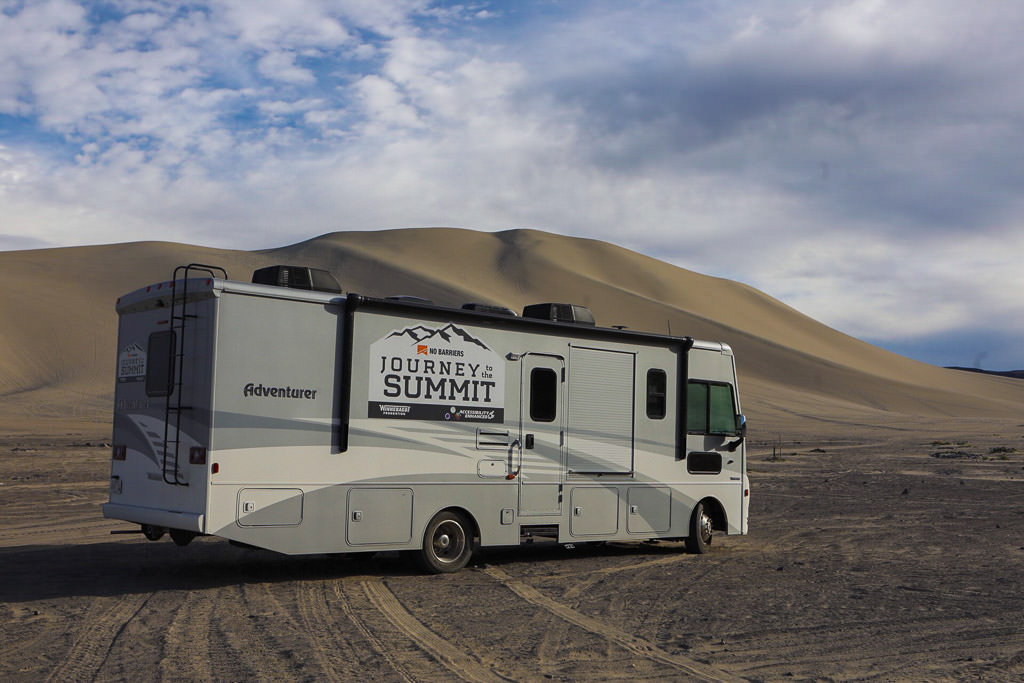 Winnebago Accessibility Equipped 30T parked next to a sand dune.