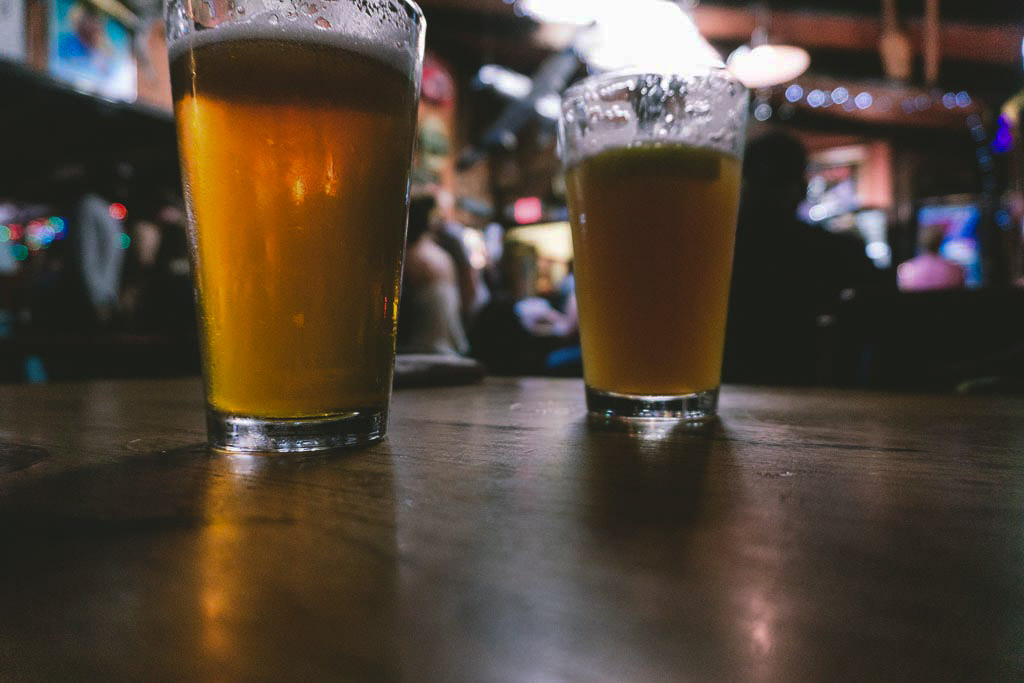 Two beers sitting on a table at a pub